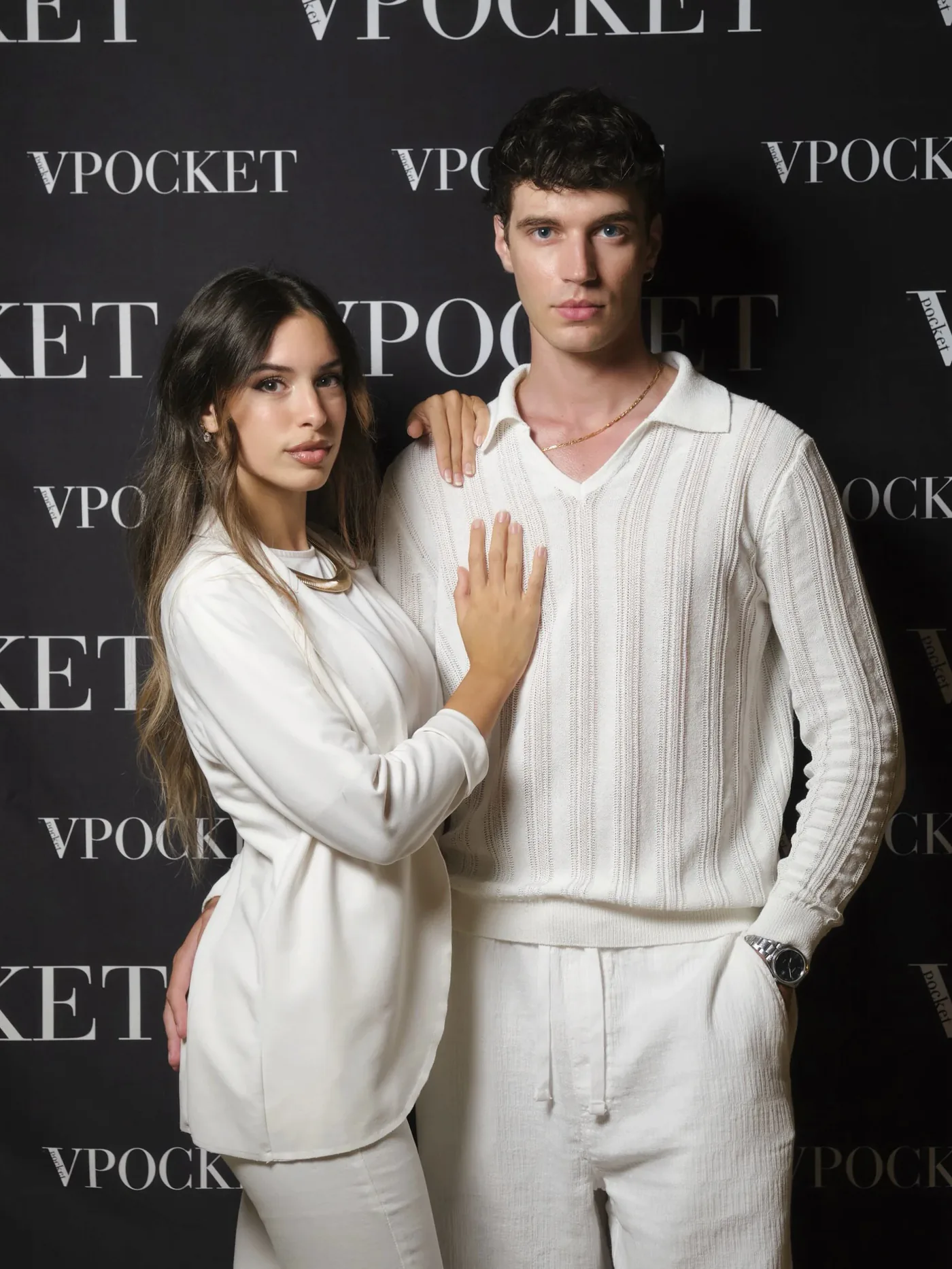 Shot of a couple in total white outfits in front of the VPOCKET event backdrop