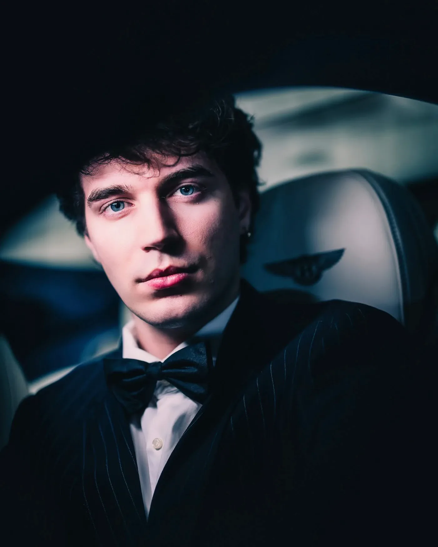 Close-up in a tuxedo and bow tie inside a car, dramatic side lighting