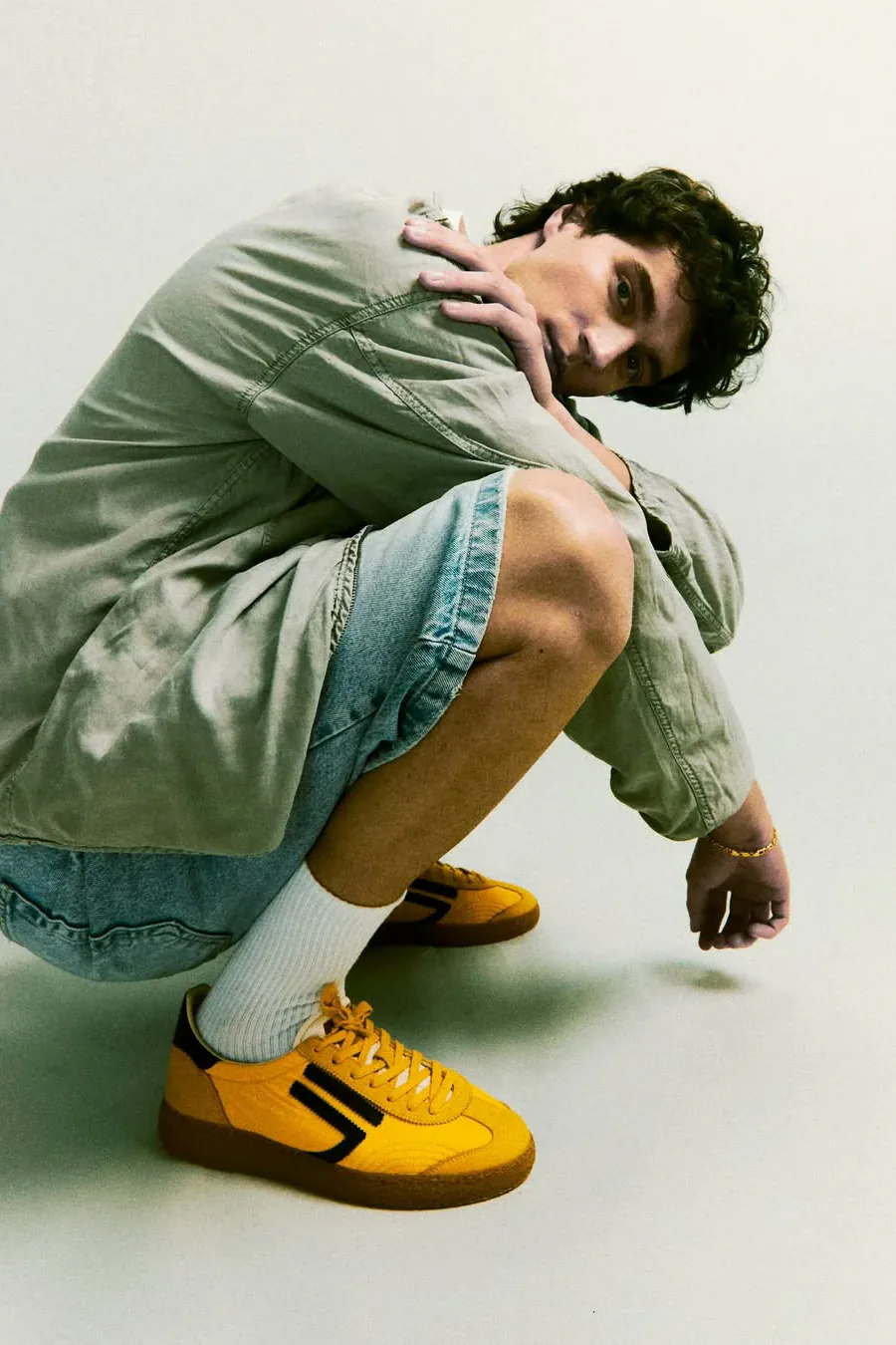 Francesco Scarparo crouching in the studio, yellow sneakers in the foreground