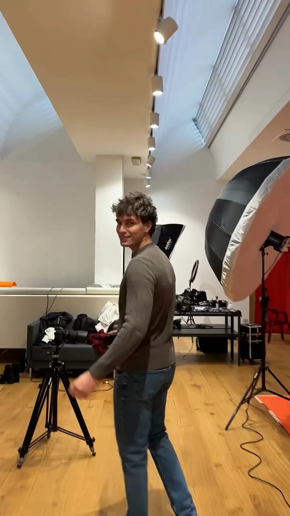 Francesco Scarparo walks across a photo studio among lights, softboxes and backdrops